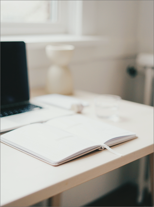 a laptop and notebook on a white table